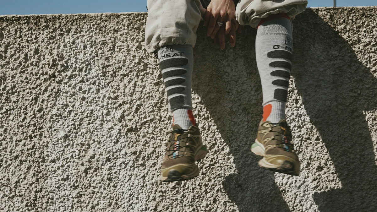 meilleures chaussettes chauffantes grises G HEAT portées avec des chaussures de trail sur un muret